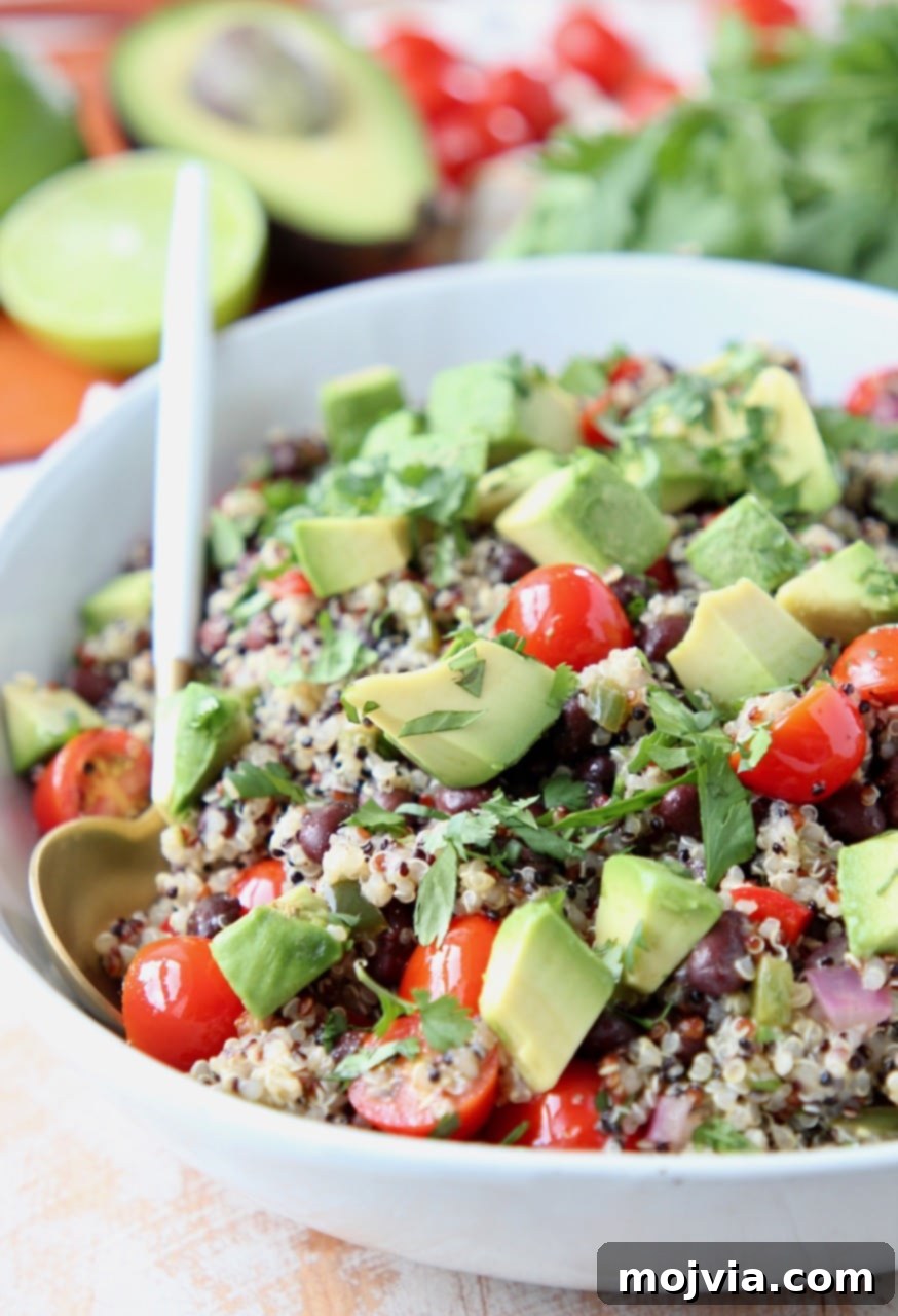 Fiesta Quinoa Salad 2 Mexican quinoa salad in bowl with white and gold spoon, topped with diced avocado