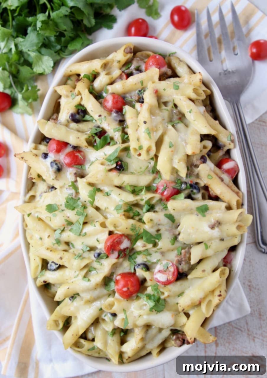 Zesty Taco Pasta Bake with Avocado Cream 2 Taco pasta in a large oval casserole dish topped with vibrant cherry tomatoes and fresh cilantro, ready to be served