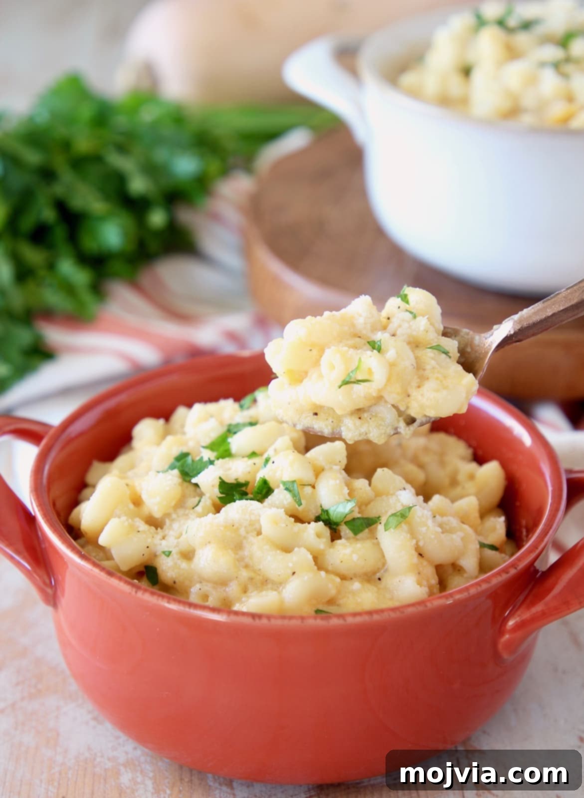 Butternut squash mac and cheese with spoonful taken out of orange crock