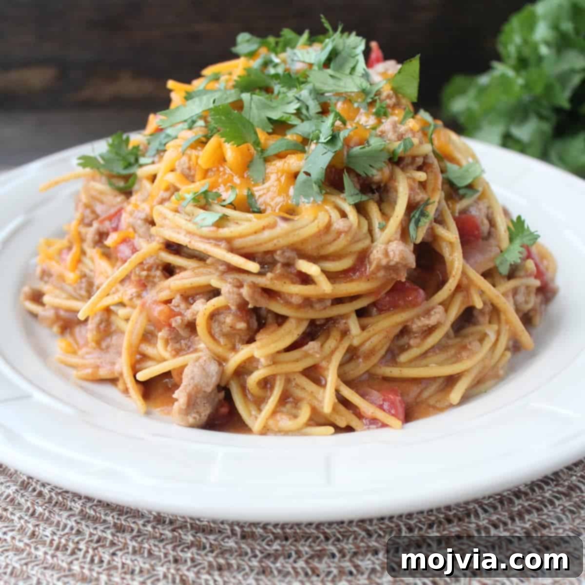 One-Pot Gluten-Free Taco Pasta 2 A top-down shot of a large pot filled with creamy, cheesy Gluten-Free Taco Spaghetti, garnished with fresh cilantro and a dollop of sour cream.