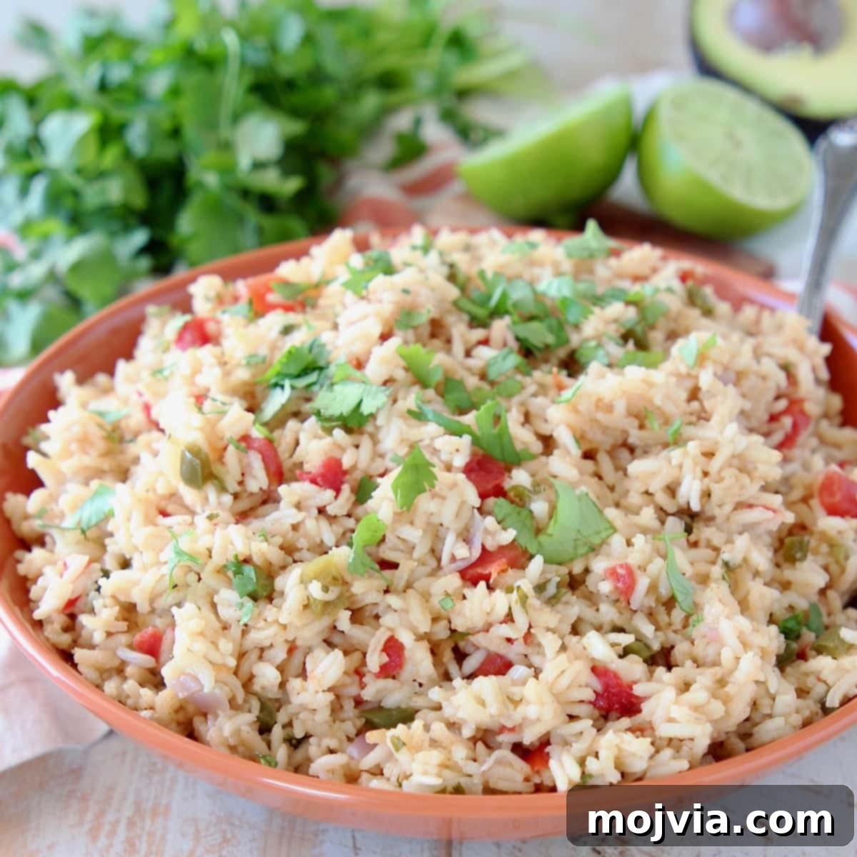 Fiesta Rice 2 Vibrant Mexican rice in an orange bowl, garnished with fresh cilantro and lime wedges, ready to serve.
