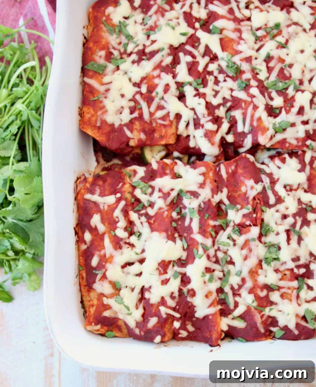 Rustic Mushroom and Squash Enchiladas 2 Classic Veggie Enchiladas with homemade red sauce baking in a white casserole dish, ready to serve.