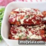 Rustic Mushroom and Squash Enchiladas 5 Enchilada with red sauce lifted out of white baking dish with spatula