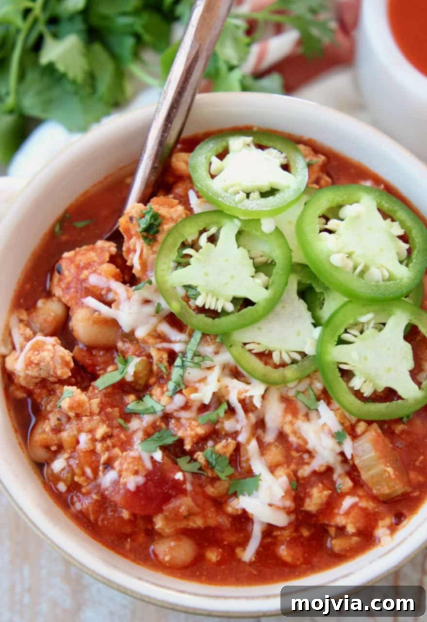 Delicious Slow Cooker Buffalo Chicken Chili served in a rustic bowl, garnished with vibrant fresh sliced jalapenos, showcasing its rich texture and inviting color, ready to be enjoyed as a healthy and flavorful meal.