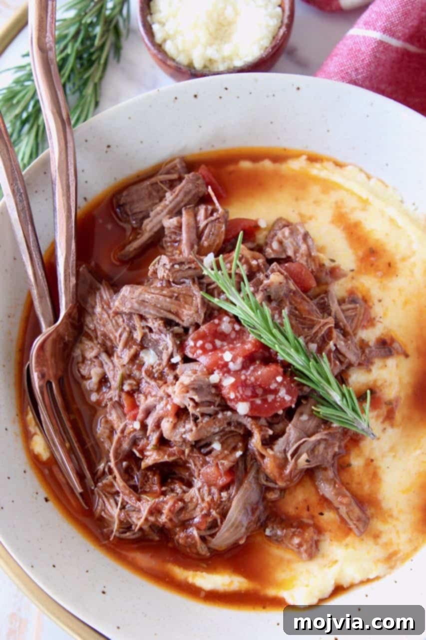 Shredded beef ragu sauce served over creamy polenta in a white bowl