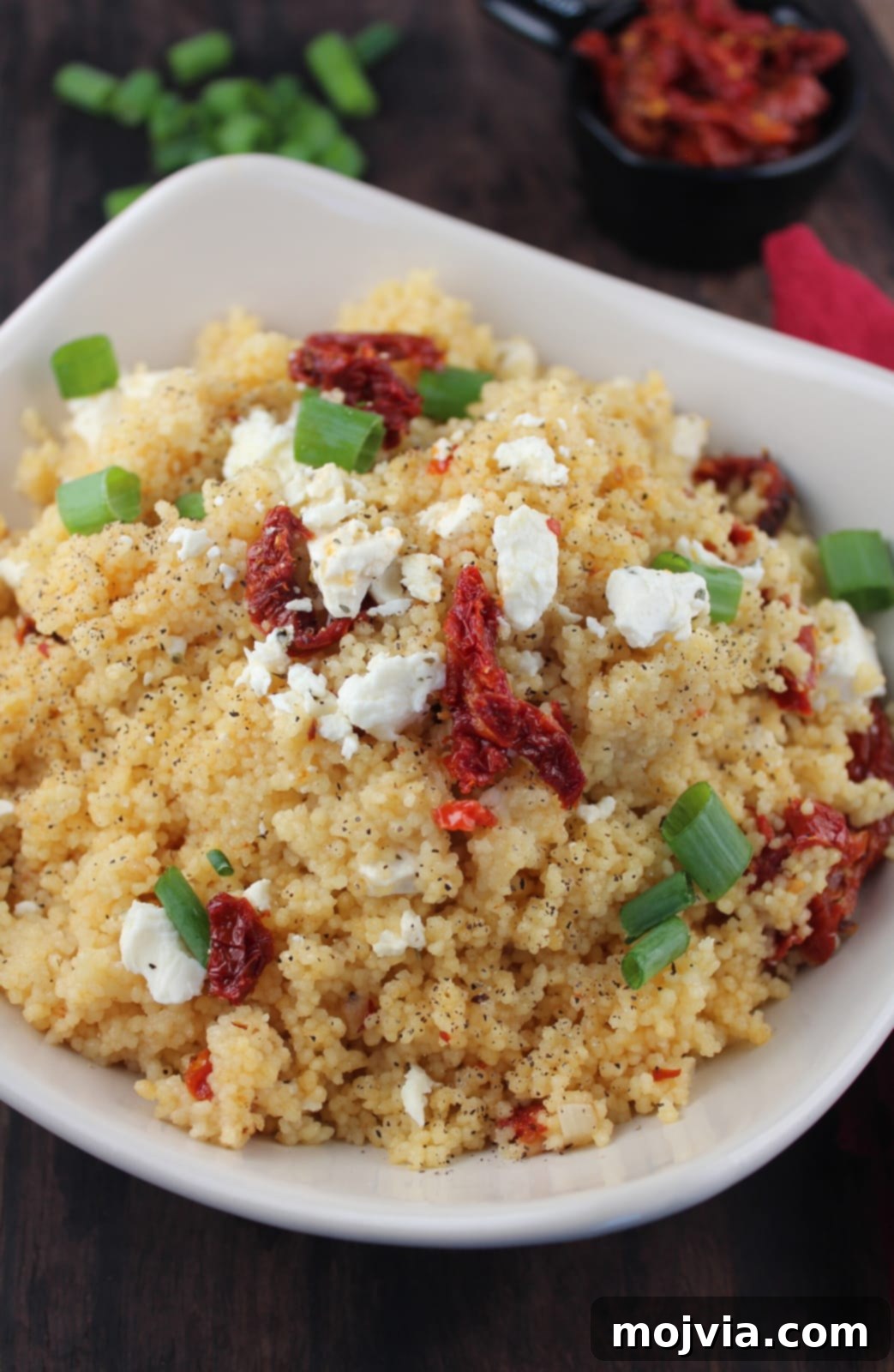 A vibrant bowl of Mediterranean Couscous Salad generously topped with crumbled feta cheese