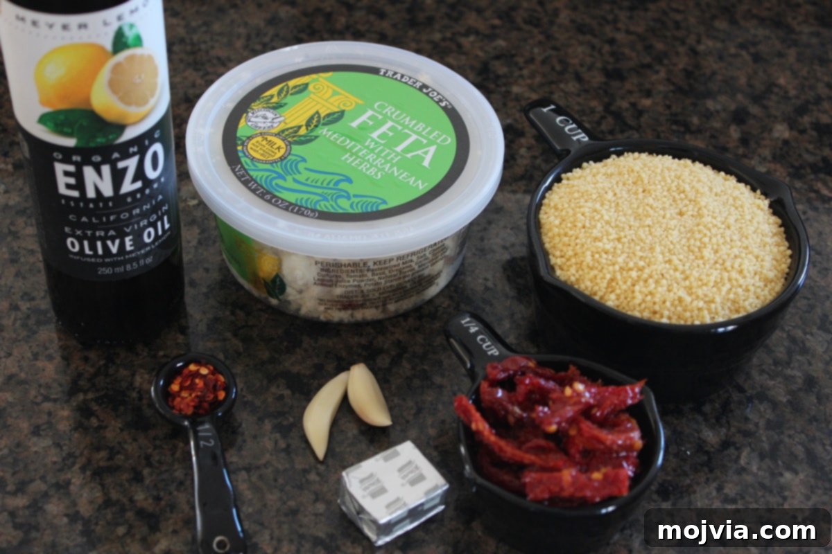 Fresh ingredients laid out for Mediterranean Couscous including couscous, sun-dried tomatoes, garlic, and feta