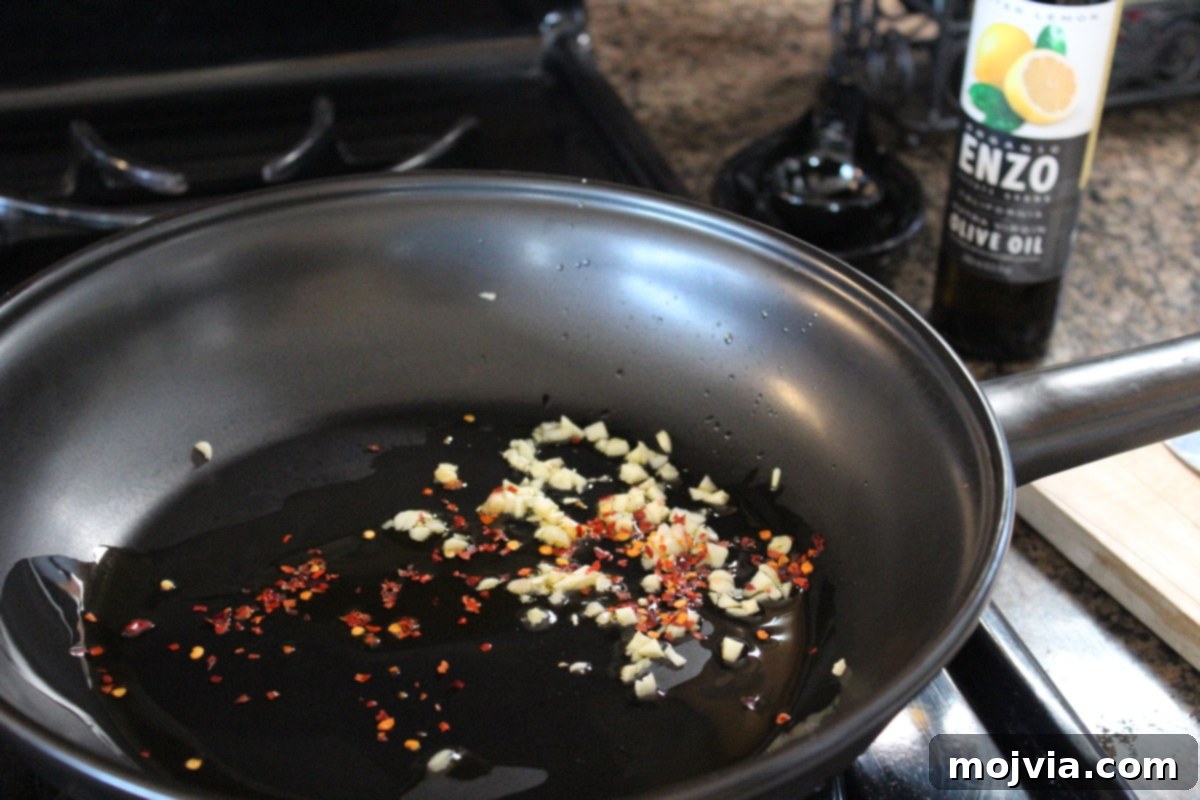 Sautéing minced garlic and red pepper flakes in olive oil in a skillet, creating a fragrant base