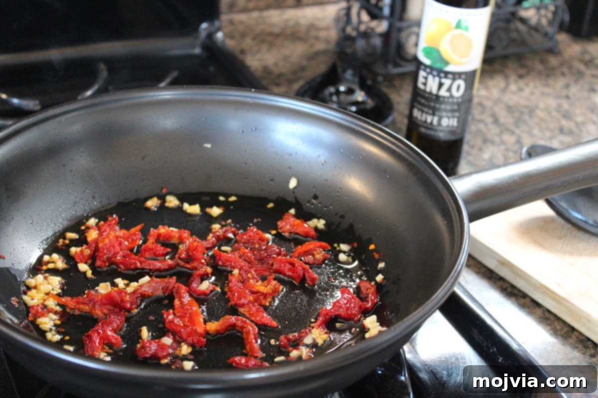 Sun-dried tomatoes added to sautéed garlic and red pepper in a skillet, gently warming to release flavors