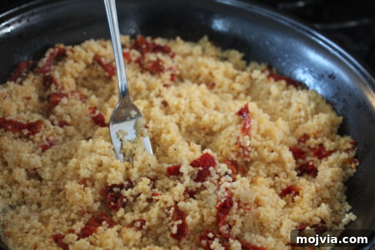 Fluffy sun-dried tomato couscous in a skillet after cooking, ready for the final touches