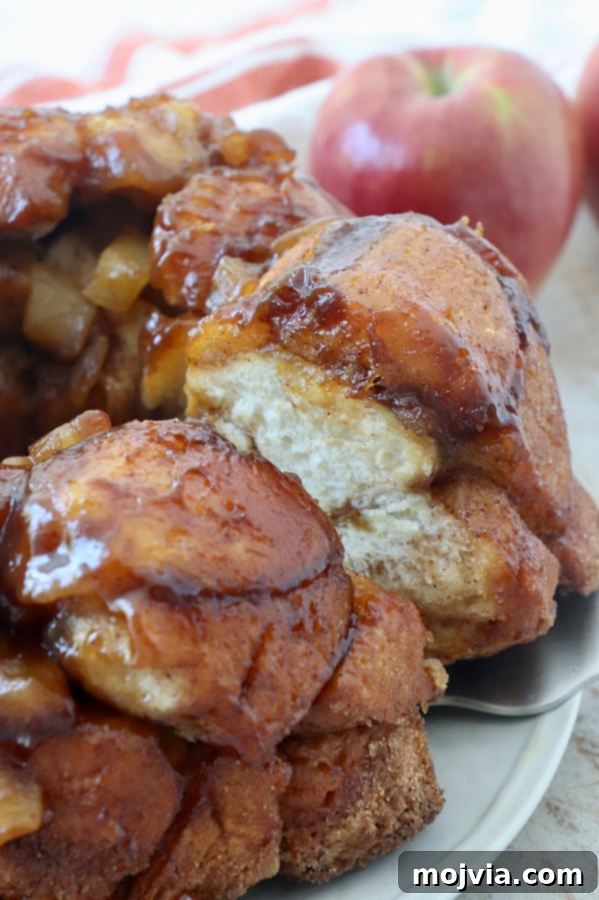 A serving of Pumpkin Apple Monkey Bread on a plate with a serving spatula, showcasing its sticky, pull-apart texture.