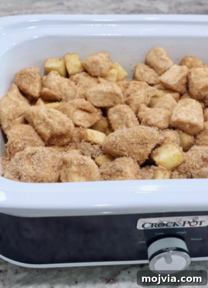 Sugar-coated diced biscuit dough layered in a Crock Pot, ready for slow cooking.