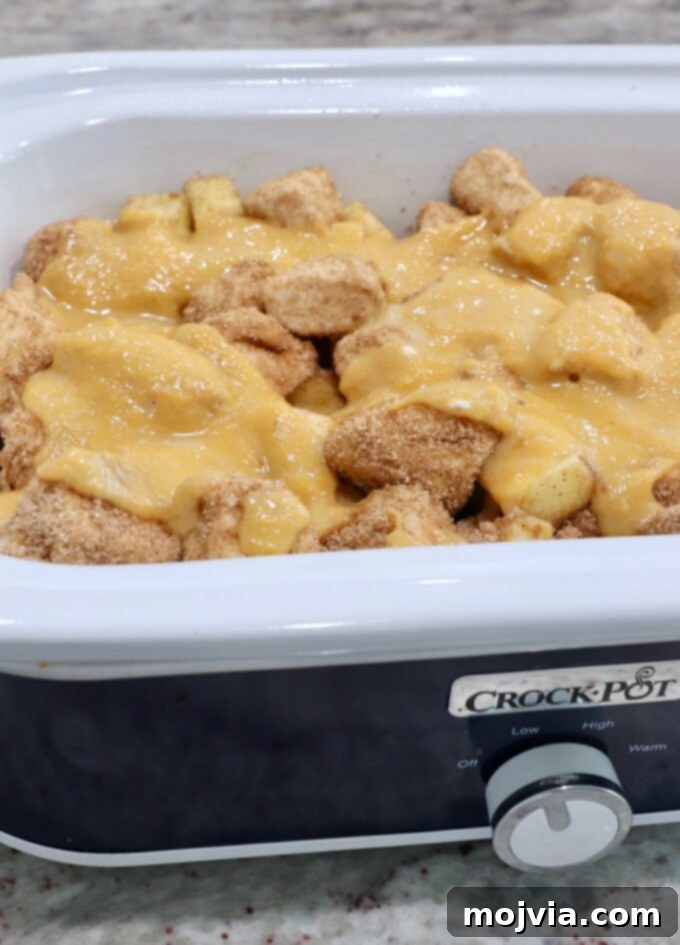 Sugar-coated diced biscuit dough in a Crock Pot, now topped with the rich pumpkin puree mixture.