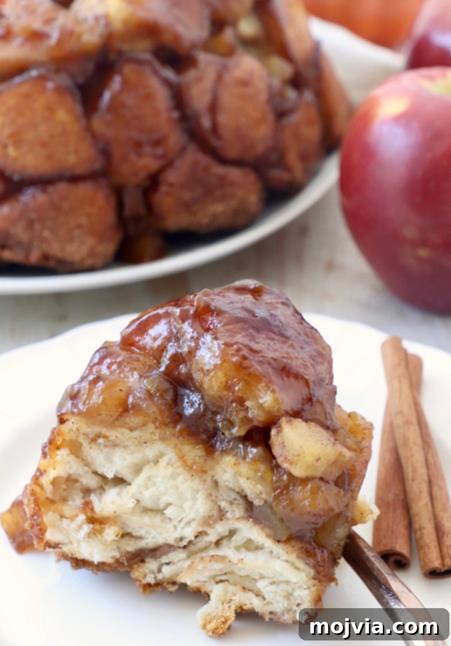 A slice of apple monkey bread on a plate, garnished with cinnamon sticks, emphasizing its inviting fall presentation.