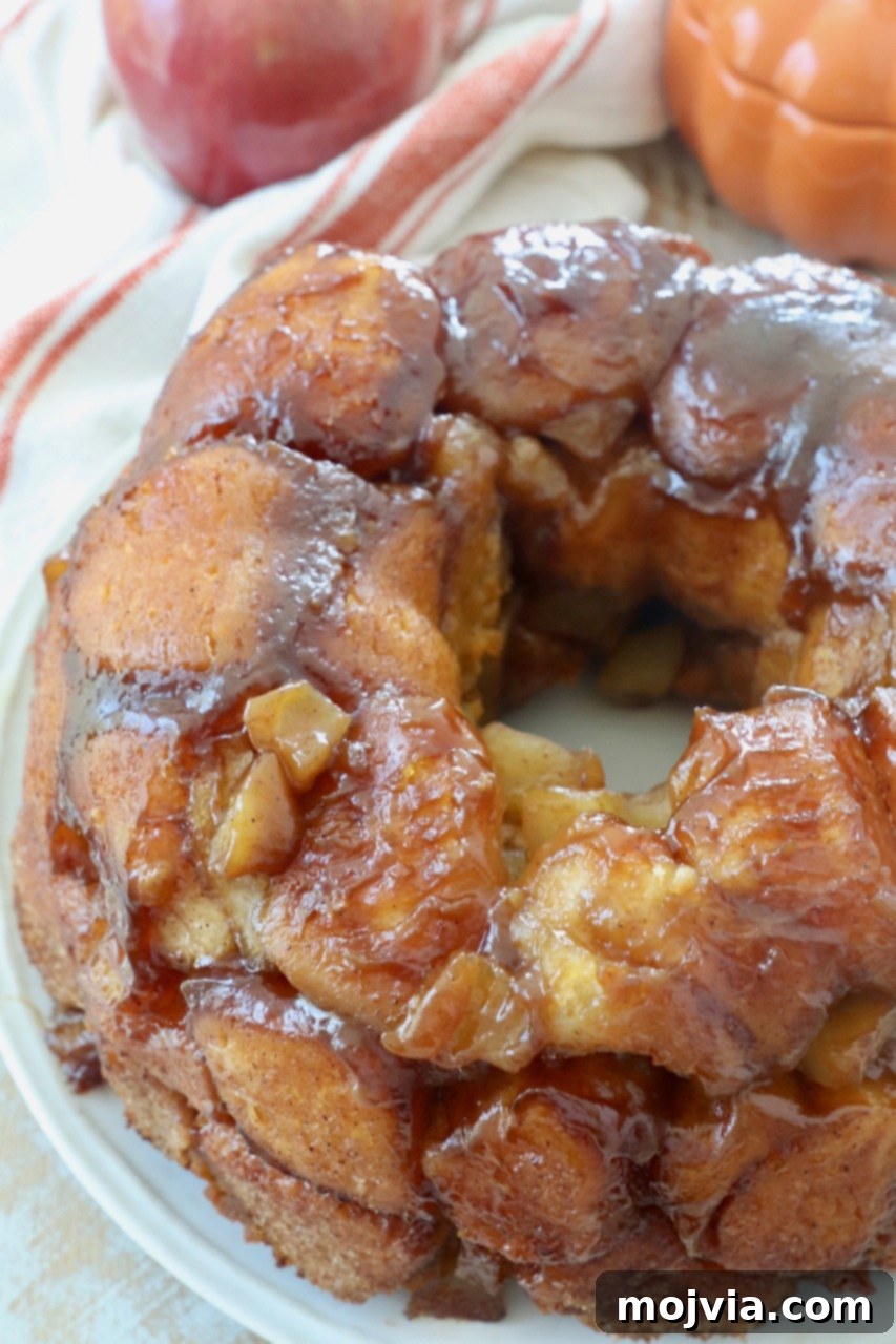 A large serving of pumpkin apple monkey bread on a white plate, highlighting its delicious fall appeal.