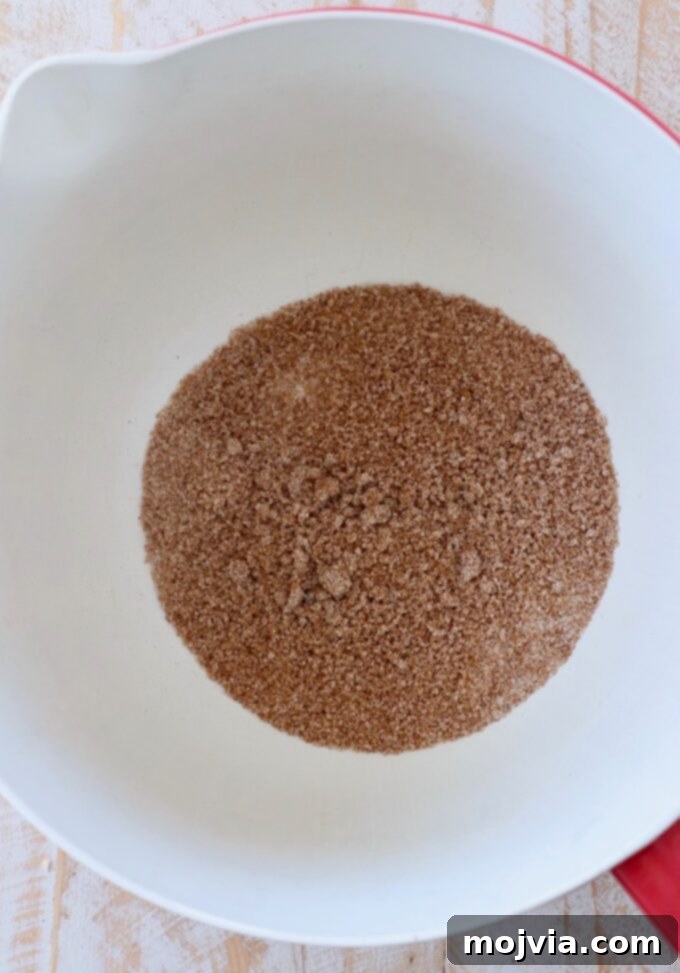 Granulated sugar, brown sugar, and pumpkin pie spice combined in a large mixing bowl.