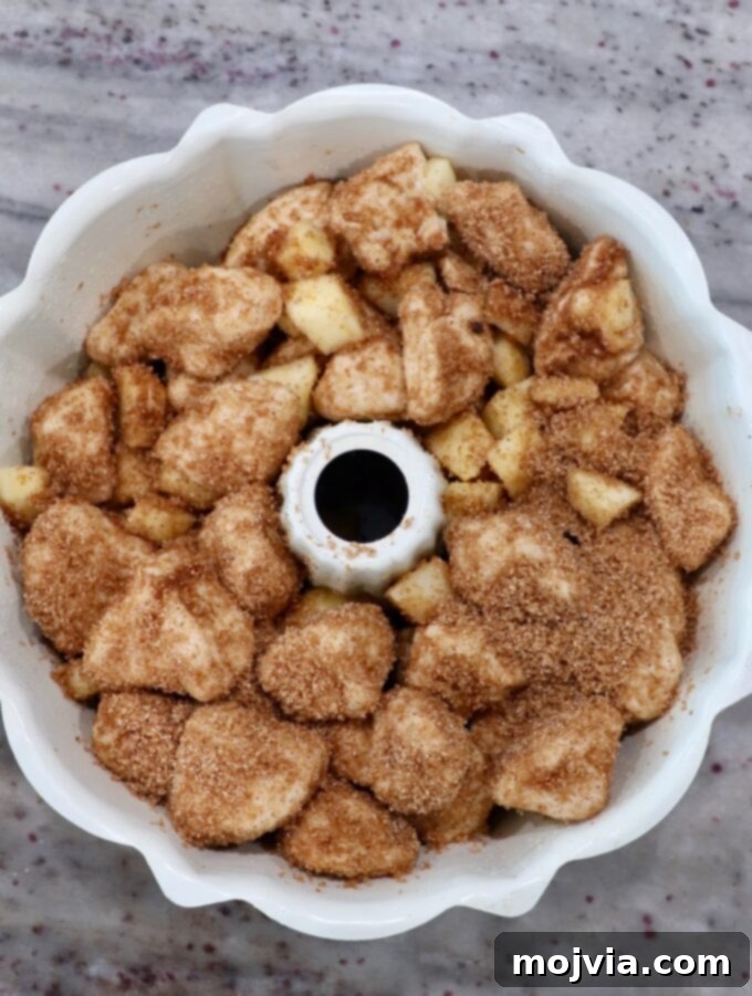 Cinnamon sugar-coated diced biscuit dough layered in a bundt pan, forming the base of the monkey bread.