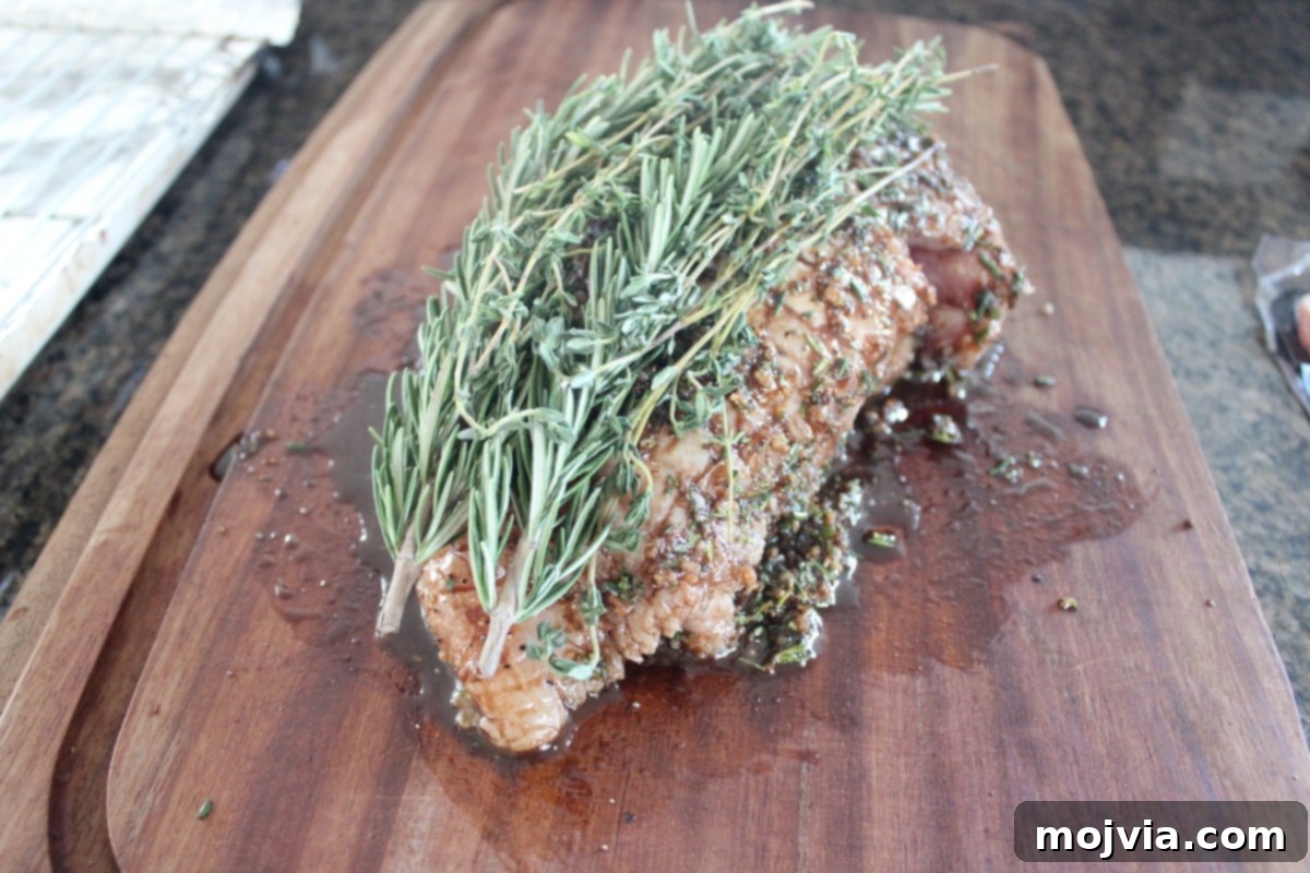 Golden Bacon Wrapped Turkey Breast 6 Fresh sprigs of rosemary and thyme placed on top of an herb-rubbed turkey breast on a wooden cutting board.