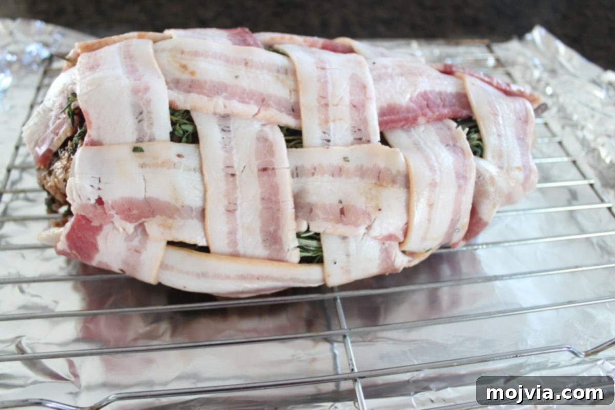 Golden Bacon Wrapped Turkey Breast 8 Bacon wrapped turkey breast placed on a wire rack over a foil-lined baking sheet, ready for the oven.