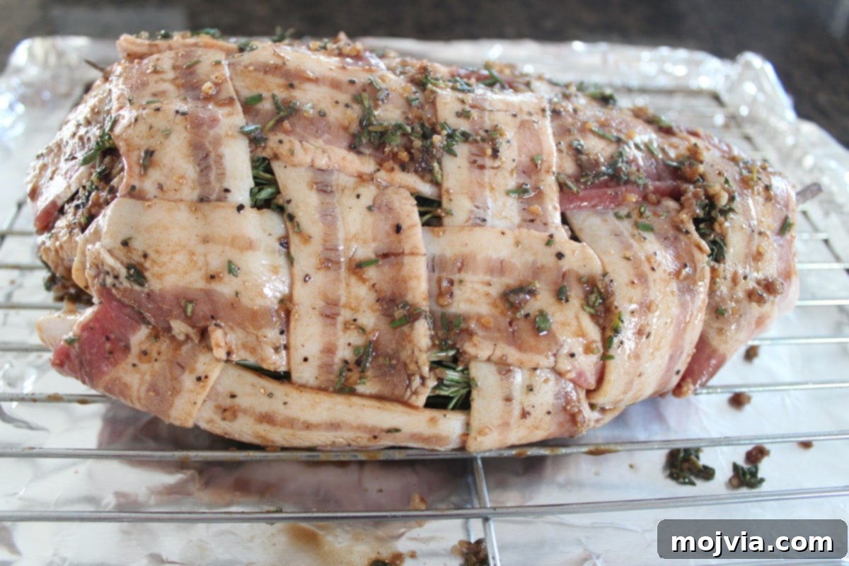 Golden Bacon Wrapped Turkey Breast 9 Herb-rubbed bacon wrapped turkey breast on a wire rack, glistening and ready to roast.