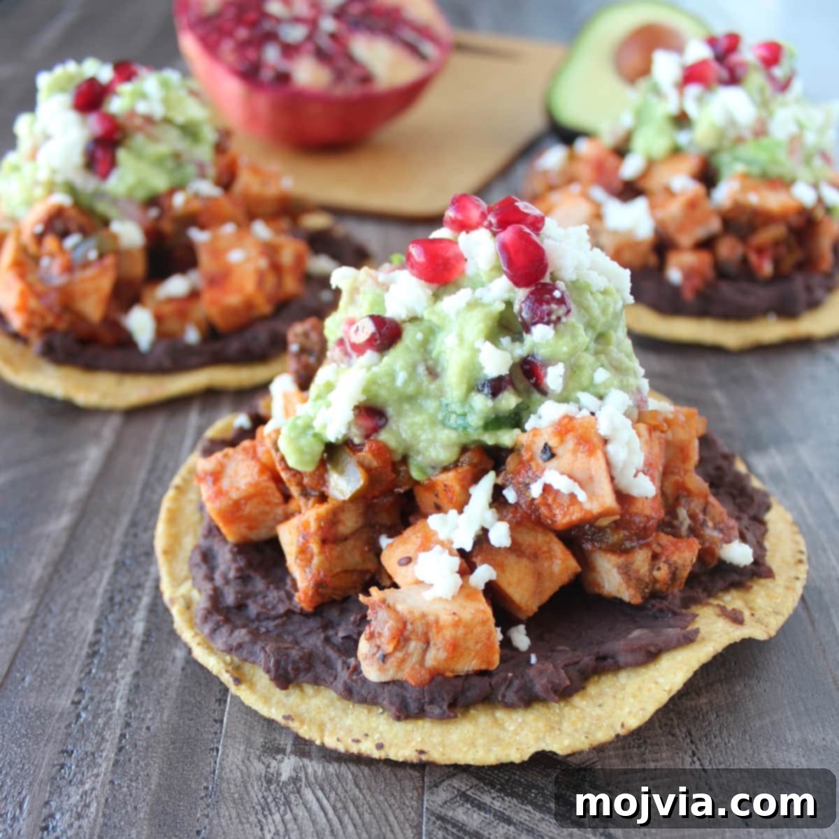 Close-up of a Turkey Tostada topped with beans, diced turkey, and pomegranate guacamole