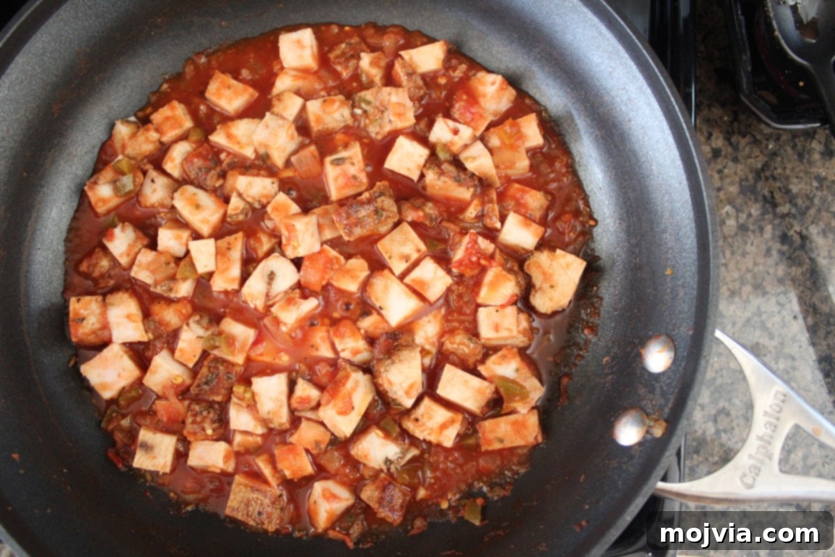 Diced cooked turkey in a skillet with salsa, heating through