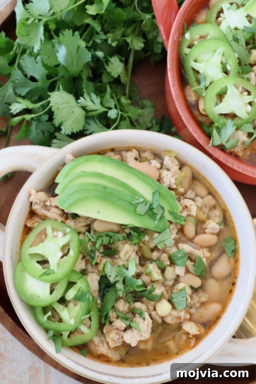 Homestyle White Chicken Chili 2 White chicken chili served in bowls, garnished with sliced jalapeños and creamy avocado