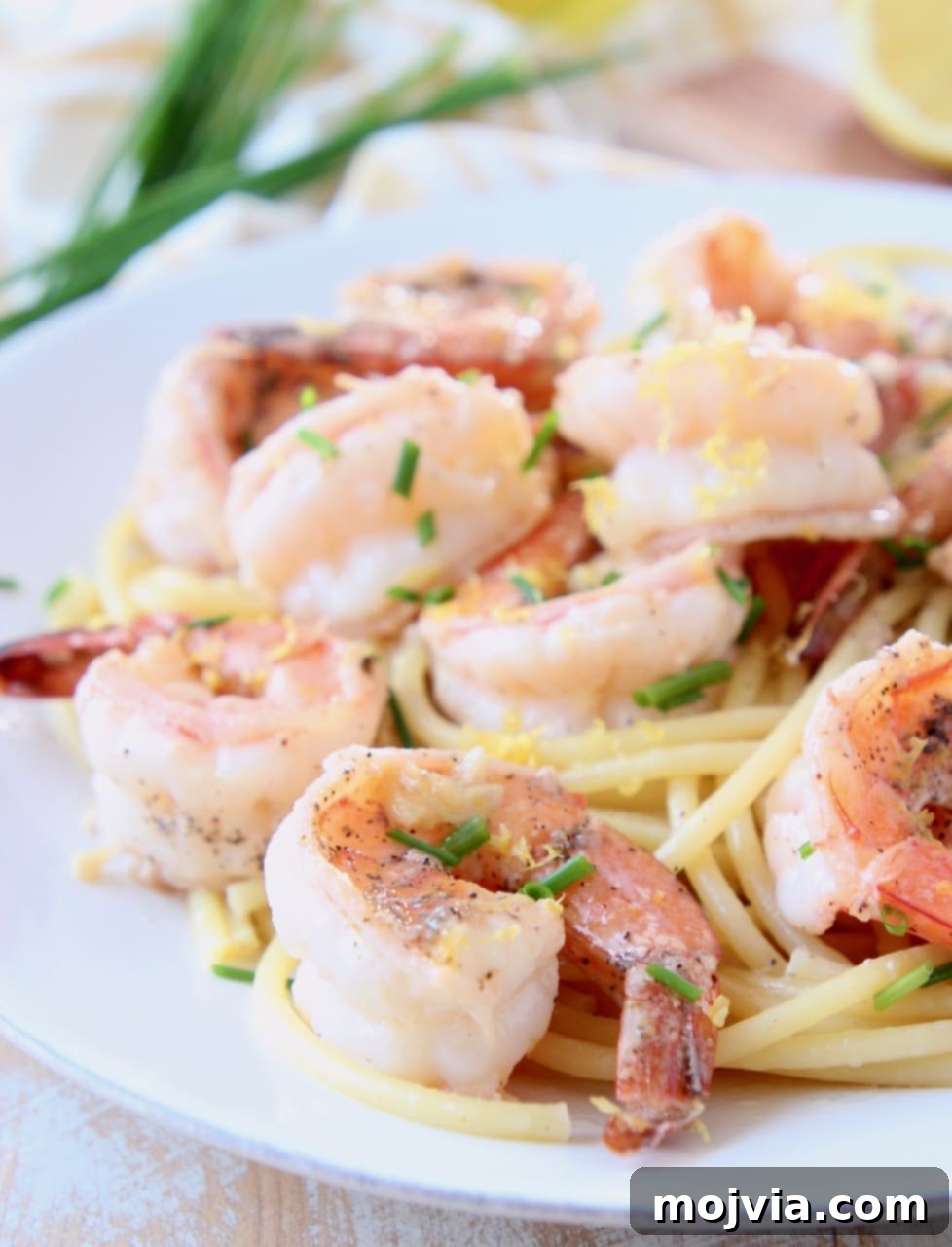 Garlic Butter Shrimp Scampi with Zesty Lemon 2 Shrimp scampi elegantly plated over bucatini pasta, garnished with fresh herbs, on a pristine white plate, showcasing a delicious and quick seafood meal.