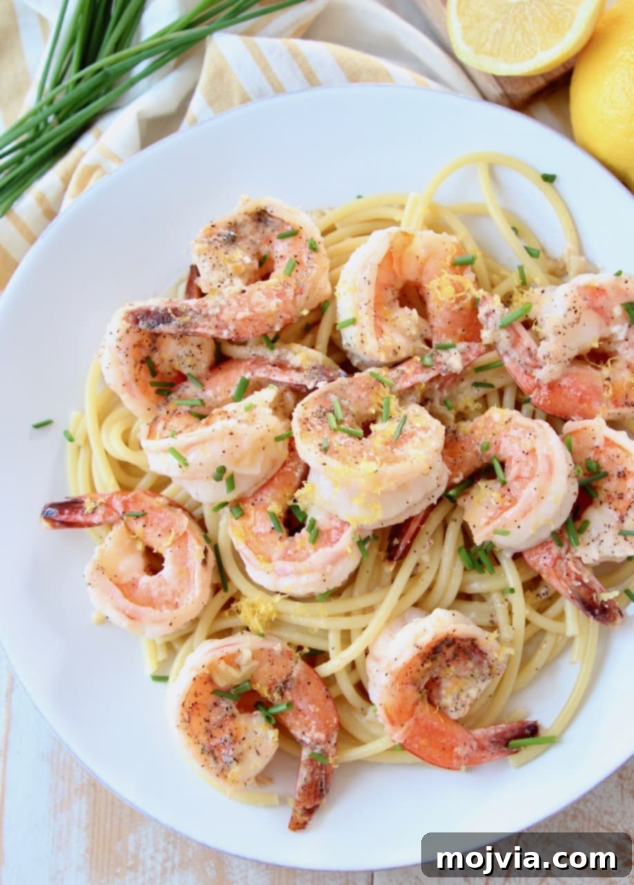 Garlic Butter Shrimp Scampi with Zesty Lemon 3 A stunning overhead shot of Lemon Butter Garlic Shrimp Scampi served on a bed of cooked pasta, garnished with vibrant fresh herbs, presented on a chic white plate.