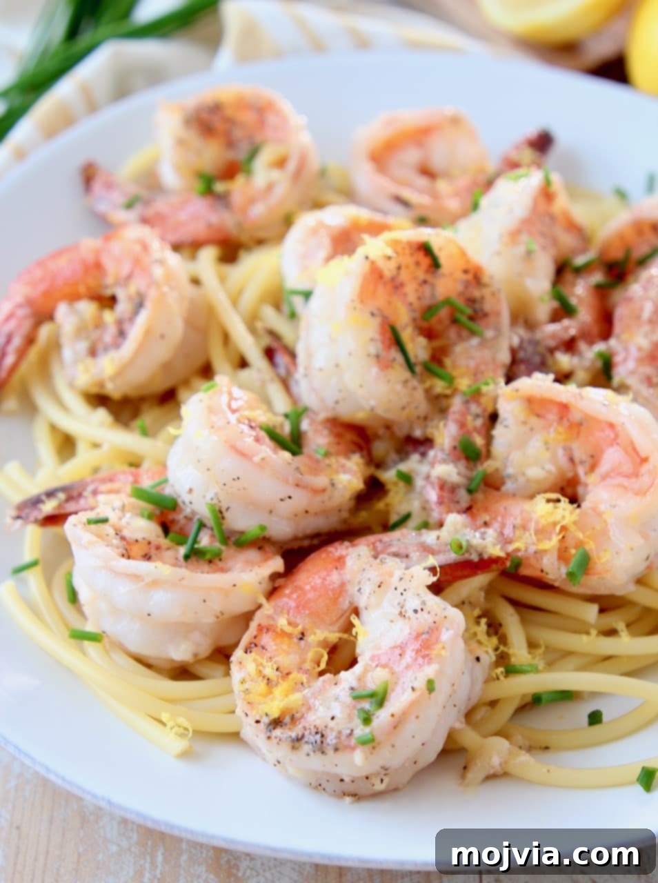 Garlic Butter Shrimp Scampi with Zesty Lemon 4 Close-up of succulent shrimp scampi served over pasta, beautifully topped with freshly chopped chives and vibrant lemon zest, ready to be enjoyed.
