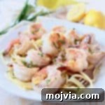 Shrimp elegantly arranged on a bed of pasta on a white plate, accompanied by a gold fork poised to twirl the noodles, illustrating a delightful meal.