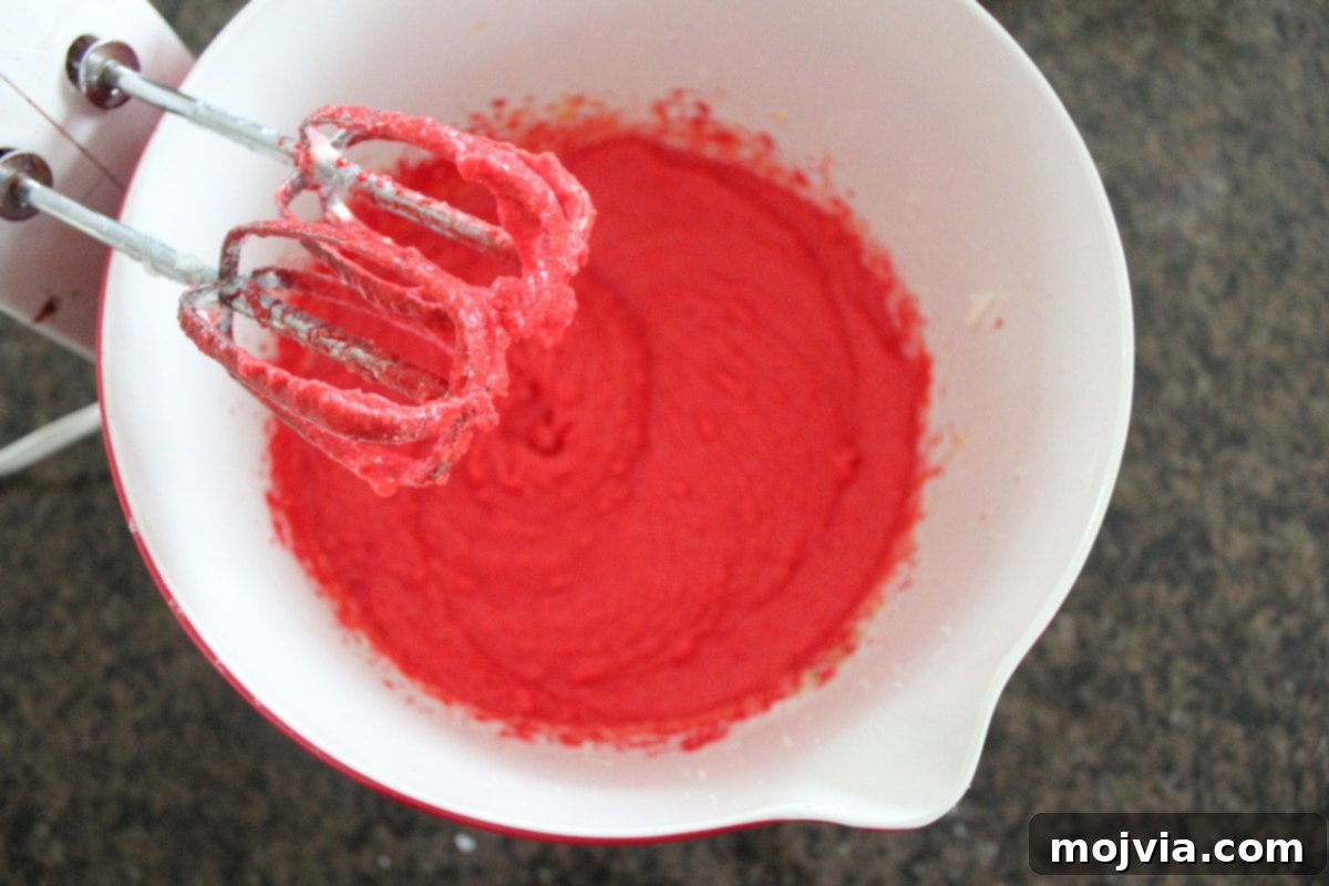 Ruby Red Brookie Bliss 5 An electric mixer resting above bright red velvet cookie batter in a bowl, showing its creamy texture.