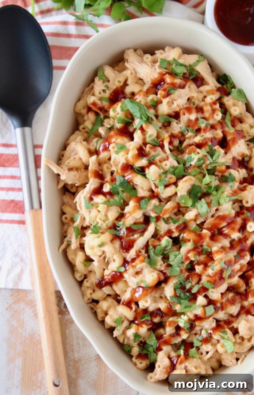Smoky BBQ Chicken Mac Bake 2 Large oval casserole dish filled with creamy BBQ Chicken Mac and Cheese, garnished with fresh chopped cilantro