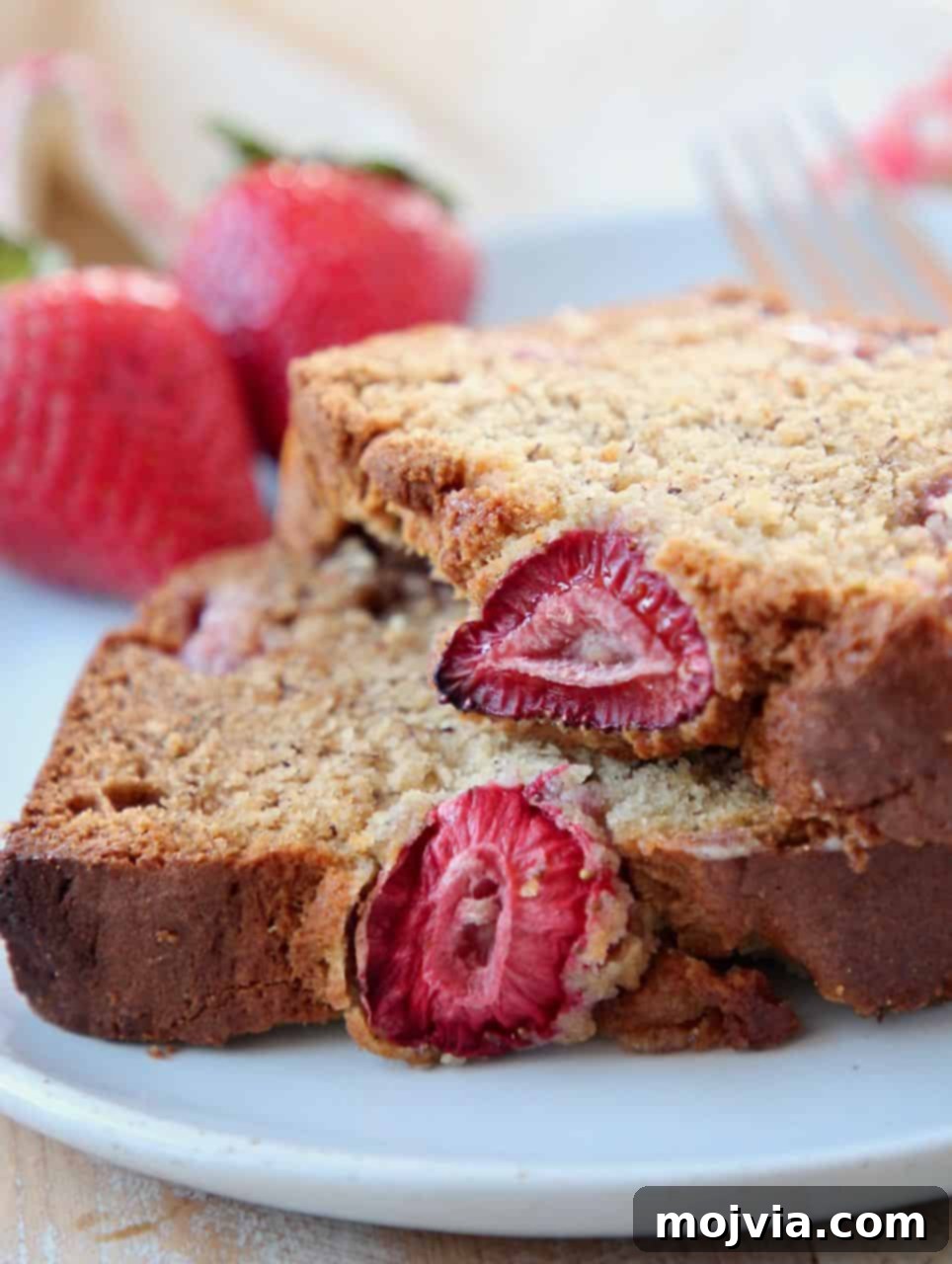 Strawberry Banana Bliss Gluten Free Loaf 5 Several perfectly baked slices of gluten-free strawberry banana bread are arranged on a white plate, showcasing their fluffy interior and beautiful fruit distribution, ready to be enjoyed.