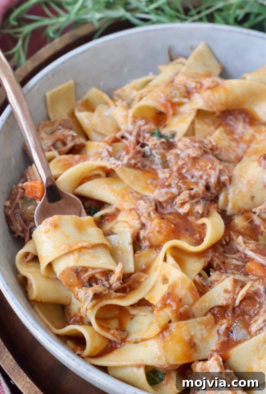 Braised Pork Ragu 12 pasta stirred in fork in bowl with pork ragu sauce