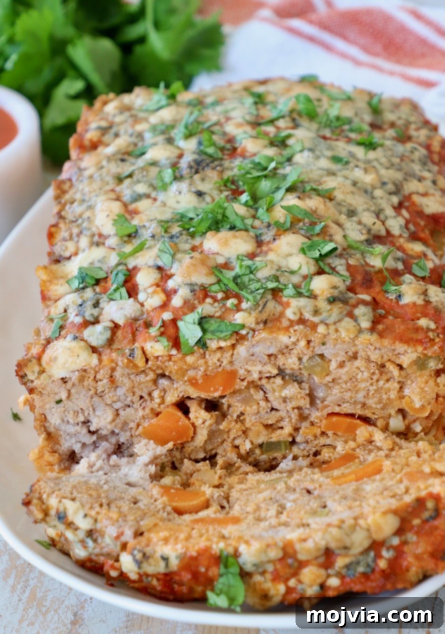 Sliced Buffalo Chicken Meatloaf on a plate, ready to be served, showcasing its juicy interior and cheesy topping.