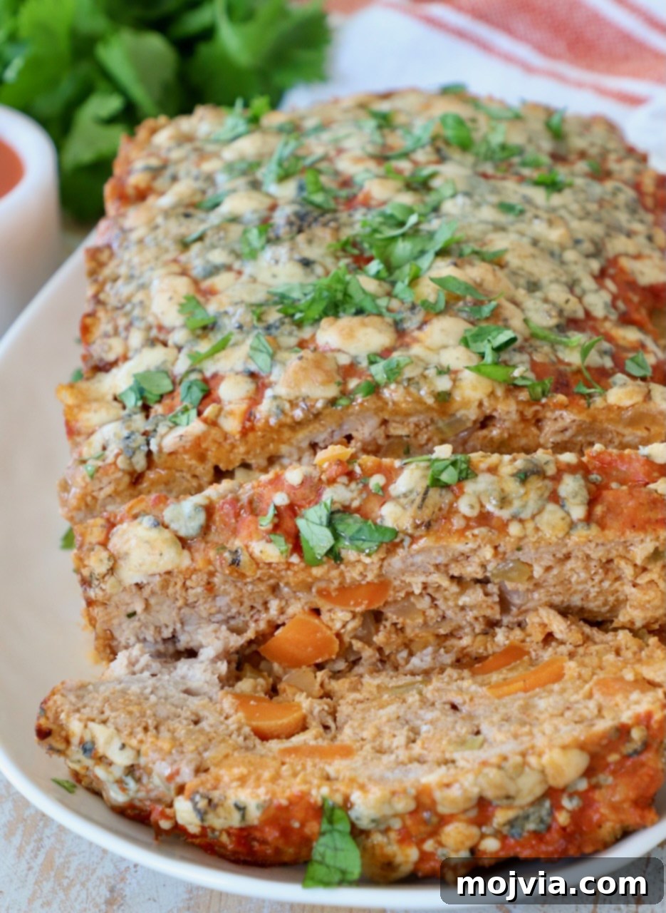A large slice of buffalo chicken meatloaf on a white plate, showing the texture of the meat and the melted cheese.