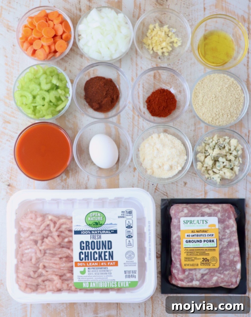 Ingredients for buffalo chicken meatloaf neatly arranged on a white wooden board, ready for preparation.