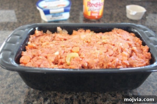 Uncooked buffalo chicken meatloaf pressed into a loaf pan, ready for the oven.