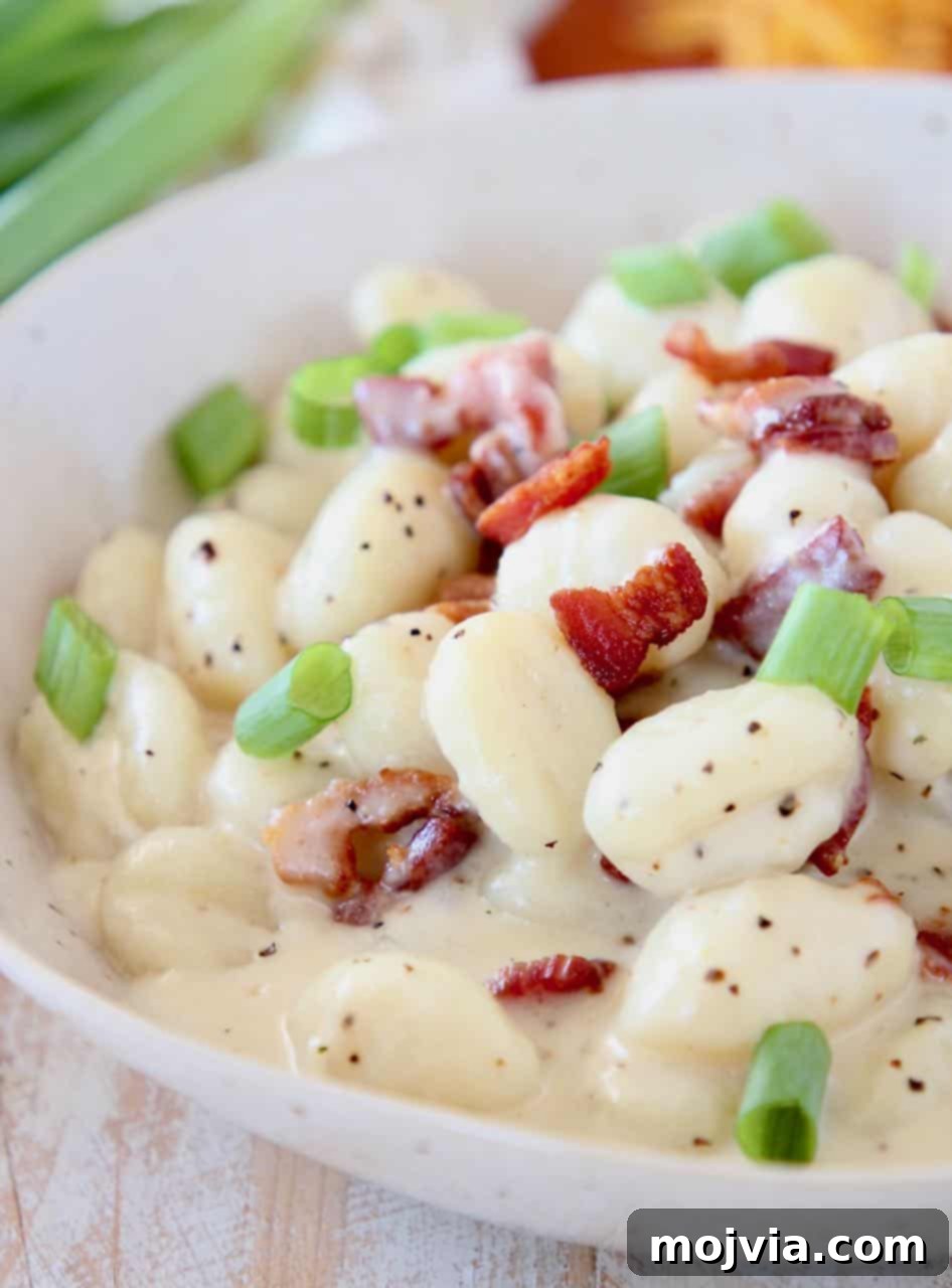 Potato gnocchi in bowl with creamy sauce, bacon pieces and diced green onions