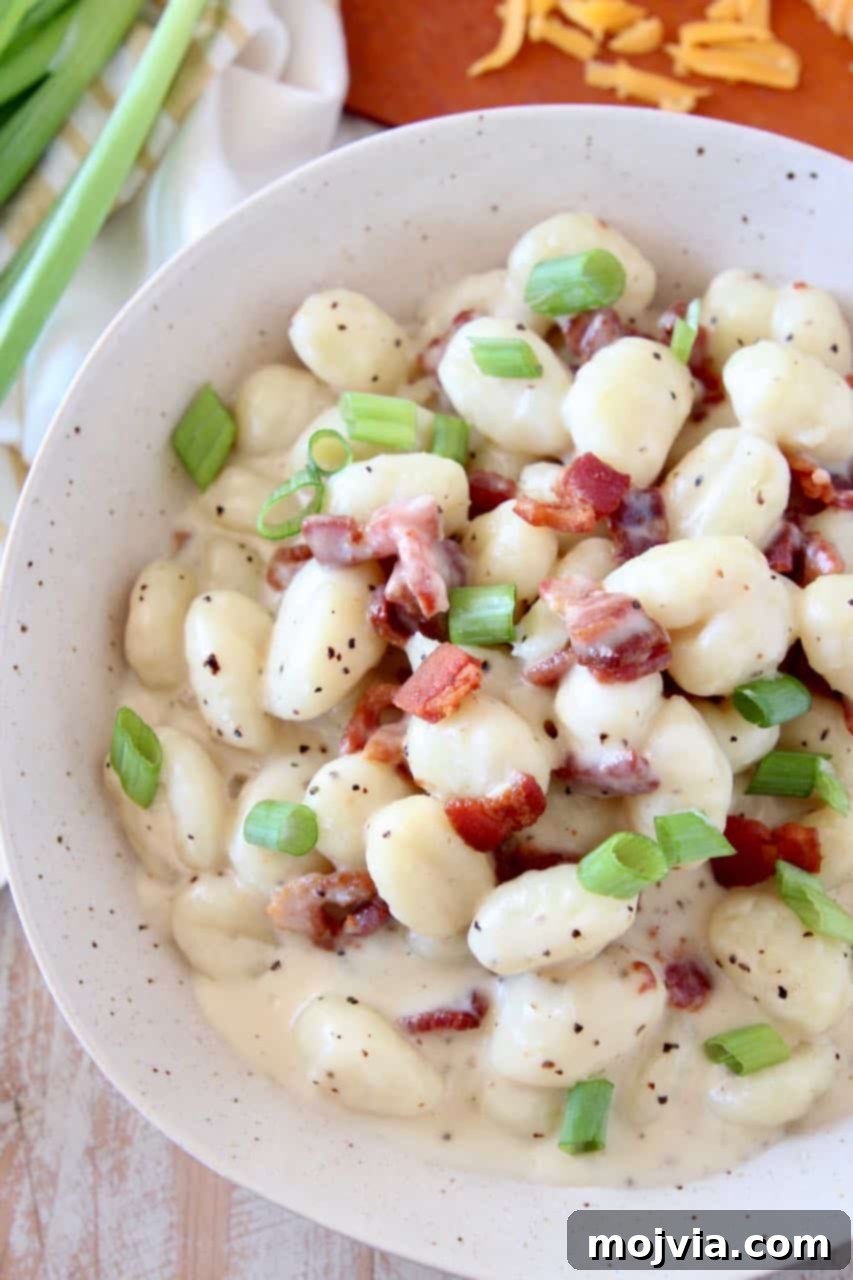 Overhead image of gnocchi in bowl with cream sauce and bacon bits