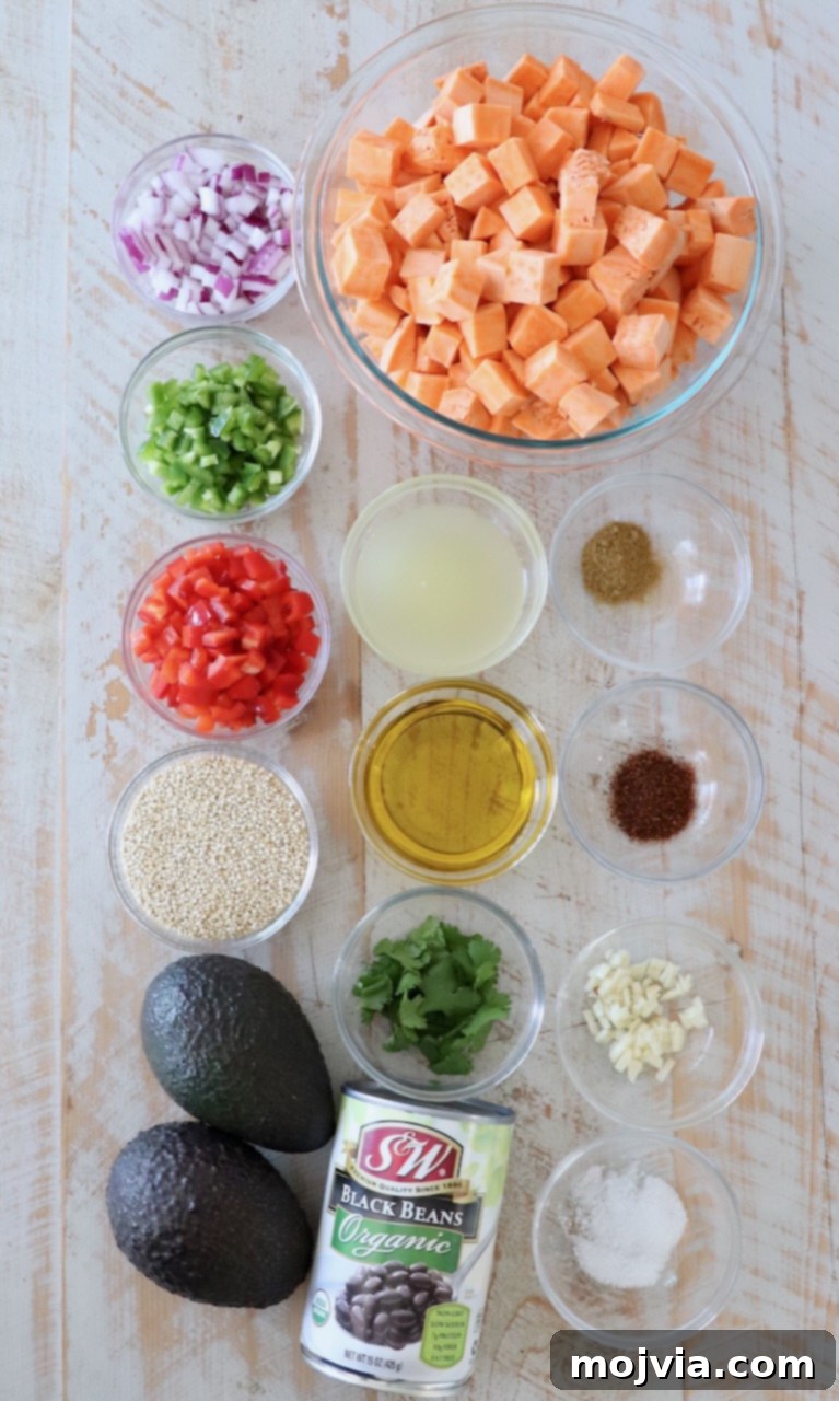 Fiesta Sweet Potato Salad 3 Fresh ingredients for Mexican Sweet Potato Salad laid out on a white wooden board, including sweet potatoes, quinoa, black beans, bell peppers, and avocado.