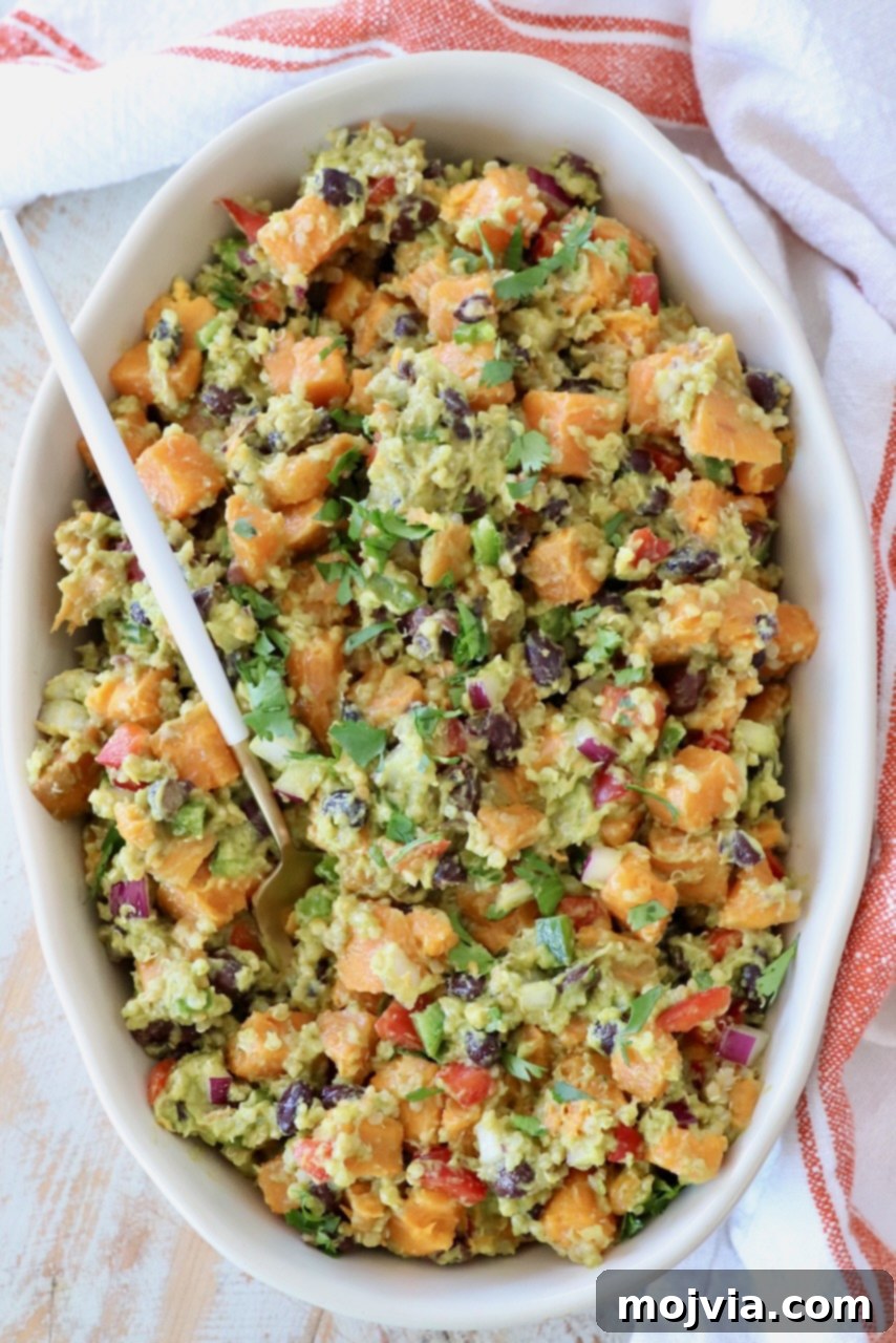 Fiesta Sweet Potato Salad 6 A large serving bowl filled with Mexican Sweet Potato Salad, ready to be enjoyed, with a serving spoon tucked in.