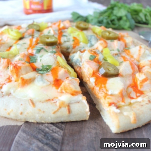 Loaded Buffalo Chicken Pizza 10 A slice of Buffalo Chicken Dip Pizza being carefully removed from the whole pizza, showcasing the melted cheese and chicken.