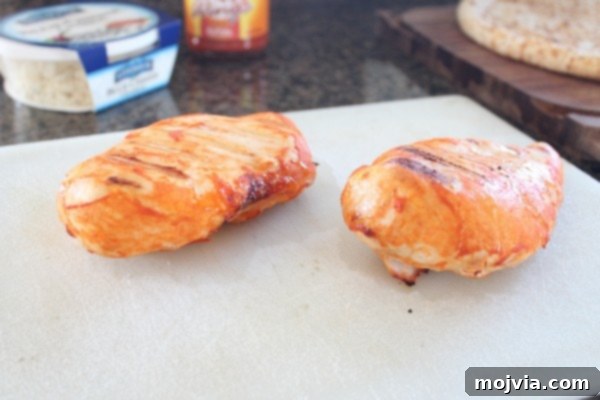 Loaded Buffalo Chicken Pizza 3 Two perfectly grilled chicken breasts resting on a white surface, ready to be diced for the pizza.
