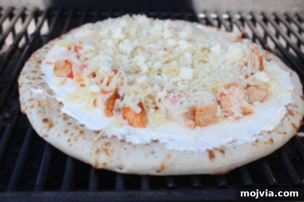 Loaded Buffalo Chicken Pizza 7 Buffalo Chicken Dip Pizza cooking on an outdoor grill, with melted cheese and bubbling toppings.