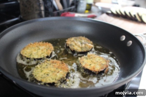 Elevated Caprese with Crispy Eggplant and Prosciutto 6 Slices of eggplant coated in breadcrumbs cooking in a pan with oil.