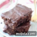 Two chocolate brownies stacked on top of each other on a plate