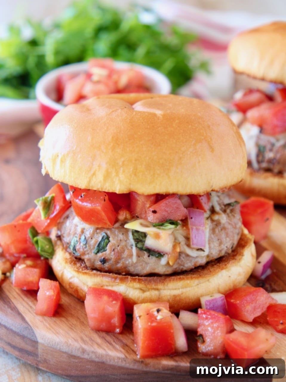 Turkey burger with tomato bruschetta on wood cutting board