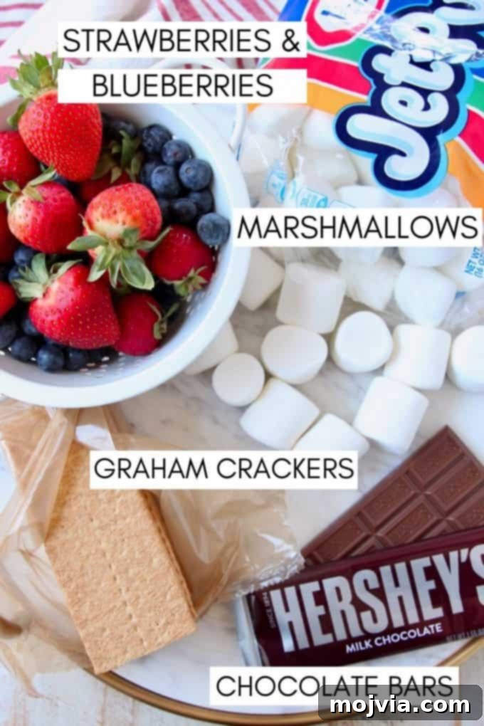 Ingredients for berry s'mores laid out: graham crackers, chocolate bars, marshmallows, fresh strawberries, and blueberries